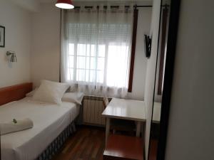 a white bed sitting next to a window in a room at Hostal Carbonara in A Coruña