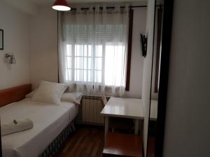 a bedroom with a white bed and white walls at Hostal Carbonara in A Coruña