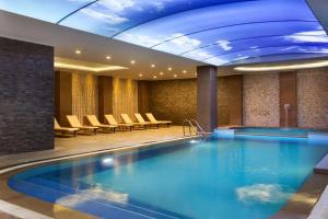 Ramada By Wyndham Bursa Cekirge Thermal & Spa في بورصة: مسبح كبير في لوبي الفندق مع الكراسي