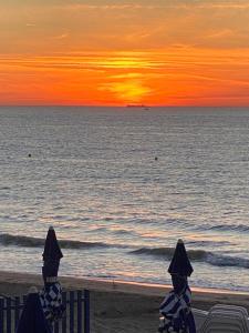a sunset on the beach with two chairs and the ocean at Manoir de la Marjolaine in Cabourg