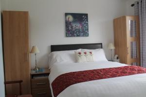 a bedroom with a white bed with a red blanket at The Meadows B&B in Armagh