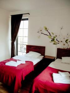 1 dormitorio con 2 camas con sábanas rojas y ventana en Oberża Złota Gęś, en Siewierz