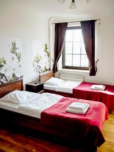 two beds in a room with red sheets and a window at Oberża Złota Gęś in Siewierz