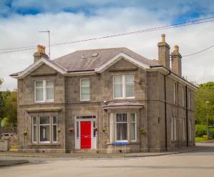 uma velha casa de tijolos com uma porta vermelha em Aden House Bed And Breakfast em Mintlaw