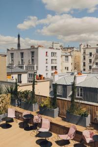 un patio all'ultimo piano con sedie, tavoli e edifici di Hôtel Wallace - Orso Hotels a Parigi