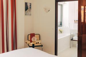 a bedroom with a bed and a chair and a bath tub at Hôtel Wallace - Orso Hotels in Paris