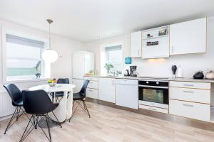a kitchen with white cabinets and a table and chairs at In the heart of Tórshavn in Tórshavn