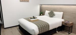 a bedroom with a large white bed with a box on it at Elm Motel in Bendigo