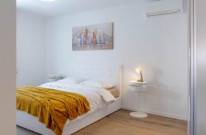 um quarto branco com uma cama com um cobertor amarelo em Apartment Ana em Kaštela