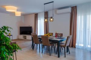uma sala de jantar com uma mesa e cadeiras e uma televisão em Apartment Ana em Kaštela