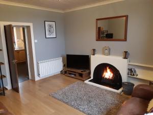 a living room with a fireplace and a television at Benside Cottage in Stornoway