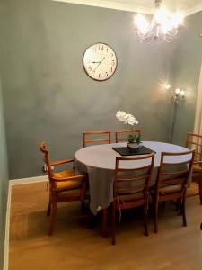 een eettafel met stoelen en een klok aan de muur bij Benside Cottage in Stornoway