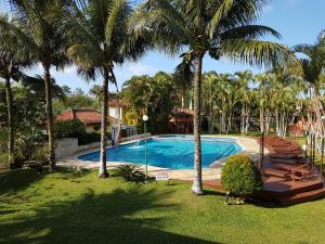 a swimming pool in a yard with palm trees at Flat 31 SUN HOUSE Maresias in Maresias