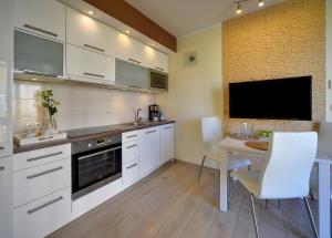 a kitchen with white cabinets and a table and a tv at Apartamenty Sun Seasons 24 - Izery in Świeradów-Zdrój