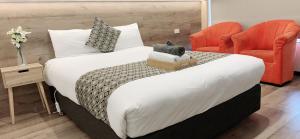 ein Schlafzimmer mit einem großen Bett mit zwei orangenen Stühlen in der Unterkunft Elm Motel in Bendigo