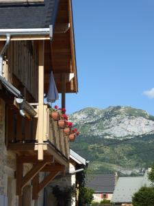 Un balcón de una casa con flores rojas. en Ferme de la grande Moucherolle, en Villard-de-Lans