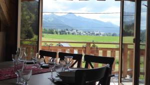 a table with wine glasses and a view of a mountain at Ferme de la grande Moucherolle in Villard-de-Lans
