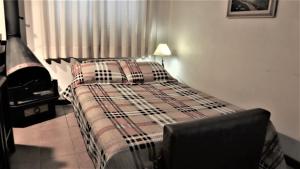 1 cama con manta a cuadros en un dormitorio en Apartamento Aconchegante + Bikes, en Gramado