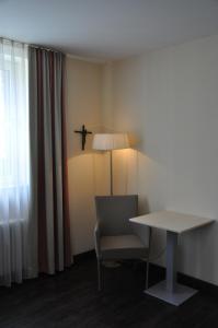 Zimmer mit einem Tisch, einem Stuhl und einer Lampe in der Unterkunft Gästehaus der Katholischen Akademie in Regensburg