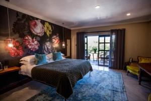 - une chambre avec un lit et une peinture murale dans l'établissement The Bohemian Guesthouse, à Tzaneen