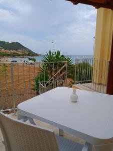 een witte tafel en stoelen op een balkon met uitzicht op de oceaan bij Affittacamere Aurora da Nonna Orsola in Villaputzu