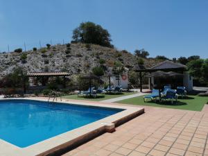 Una piscina con sillas y una montaña al fondo. en Casa Rural El Puerto, en El Chorro