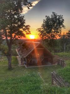 una casa en un campo con la puesta de sol en el fondo en Puckó, en PerÅ‘csÃ©ny