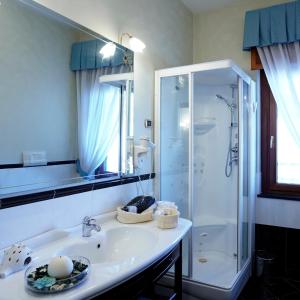 a white bathroom with a shower and a sink at Hotel Capys in Capua