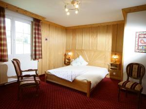 a bedroom with a bed and two chairs and a window at Maison d'hôtes La Cerisaie in Breitenbach