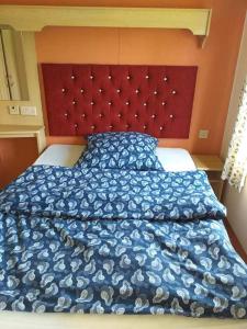 a bed with a blue blanket and a red headboard at Na Piaskach Domek na Roztoczu in Narol