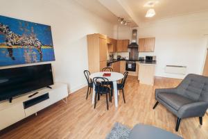 a living room with a table and chairs and a television at The Stay Company, Dalby House in Derby