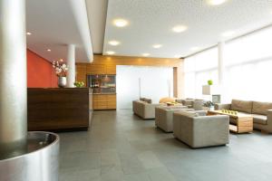 ein Wohnzimmer mit Sofas und Stühlen in der Lobby in der Unterkunft ACHAT Hotel Corbin München Airport in Freising