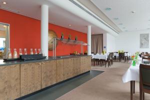 ein Restaurant mit roten Wänden und ein Esszimmer mit Tischen in der Unterkunft ACHAT Hotel Corbin München Airport in Freising