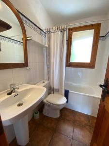 uma casa de banho com um lavatório, um WC e uma janela. em Can Janpere II em Pardines