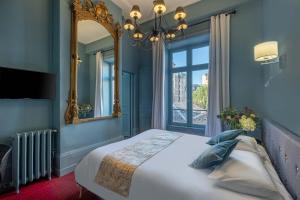 - une chambre avec un grand lit et un miroir dans l'établissement Hôtel de Paris, à Limoges