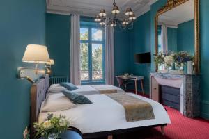 a blue bedroom with two beds and a mirror at Hôtel de Paris in Limoges
