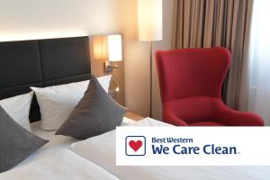 a red chair sitting on a bed in a hotel room at Best Western Queens Hotel Pforzheim-Niefern in Pforzheim