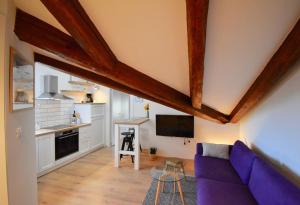 a living room with a purple couch and a kitchen at Brand New Top Centre Apartment in Pula