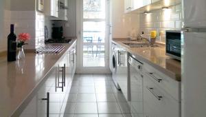 cocina blanca con armarios blancos y ventana en Apartment Las Tres Piedras en Conil de la Frontera