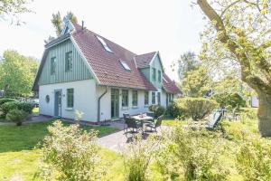 ein grünes und weißes Haus mit einem Tisch und Stühlen in der Unterkunft Ferienhaussiedlung Strandperlen Sanddornhof 3a (Typ VIII) in Wustrow