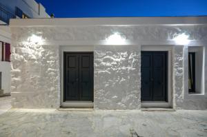 two black doors on the side of a white building at Diadema Apartments in the Town in Naxos Chora