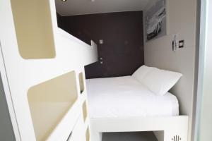 um pequeno quarto com beliches brancos em Snoozebox Olympic Park em Londres