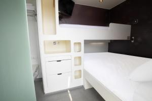 a small bedroom with white cabinets and a bed at Snoozebox Olympic Park in London