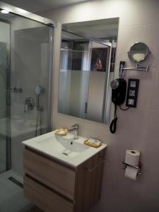 a bathroom with a sink, mirror, and bathtub at Hostal Don Suero de Quiñones in Hospital de Órbigo