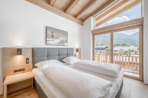 a bedroom with a large bed and a large window at AlpenParks Chalet & Apartment Alpina Seefeld in Seefeld in Tirol