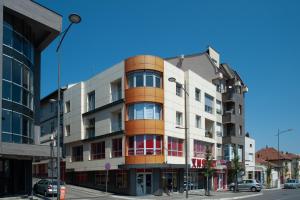 a building on a city street with cars parked at Apartman Tri S in Arandjelovac