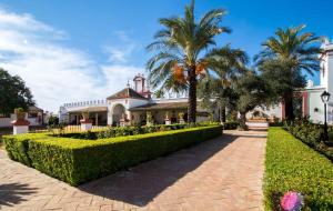 a house with a palm tree and a brick driveway at Hacienda de Orán in Utrera