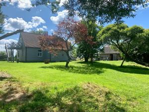 a house in a yard with trees in the grass at Lejnieki Apartment 2 in Pape