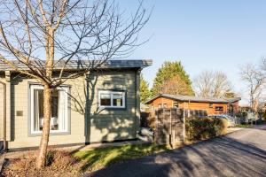 a house with a tree next to a street at Roydon Marina Village Lodges in Roydon