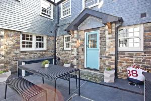 a patio with a table and benches and a blue door at Juliot 5 Star Gold Award Luxury Cottage in St Ives
